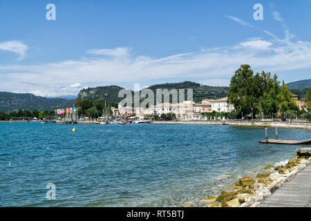 BARDOLINO, Gardasee, Italien - 7. AUGUST 2017: Panoramablick von Bardolino mit Hafen und der Promenade entfernt. Berge mit Zypressen und Olivenbäumen und v Stockfoto