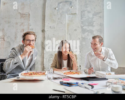 Gerne Kollegen in der Mittagspause mit Pizza in Konferenzraum Stockfoto