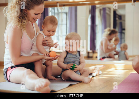 Mutter mit Spielen/Babys sitzen auf Yoga Matte Stockfoto