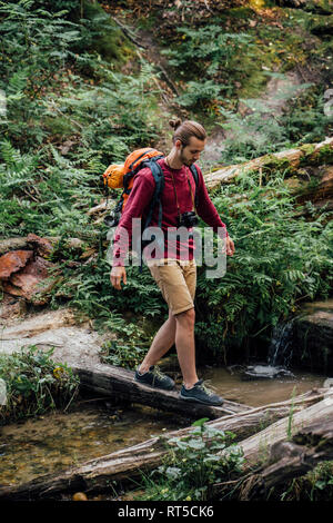 Junge Wanderer mit Rucksack über Wasser in den Wald Stockfoto