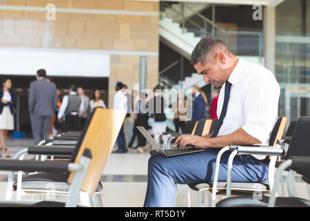 Geschäftsmann sitzt auf einem Stuhl und mit Laptop im Konferenzraum Stockfoto