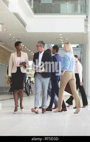 Diverse Geschäftsleute interagieren beim Gehen in der Lobby Büro Stockfoto