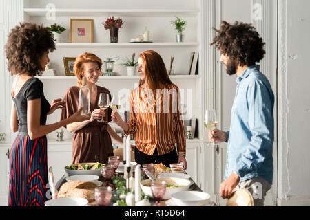 Freunde trinken Wein bei einem Abendessen, klirren Gläser Stockfoto