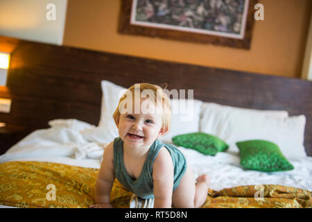Baby Mädchen auf dem Bett im Hotel Zimmer Stockfoto