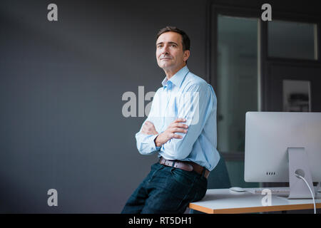 Zuversichtlich Geschäftsmann lehnte sich gegen den Schreibtisch im Büro Stockfoto