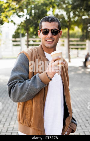 Portrait von modischen jungen Mann Sonnenbrille tragen und halten Kaffee zum Mitnehmen Stockfoto