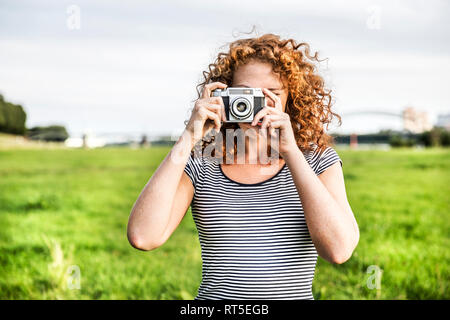 Junge Frau auf einer Wiese unter Bild der Viewer mit Kamera Stockfoto