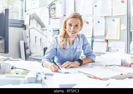 Porträt der lächelnde Frau Schreibarbeit tun am Schreibtisch im Büro Stockfoto