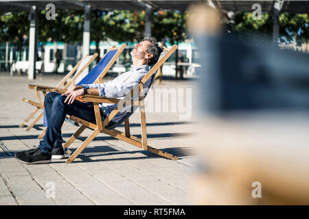 Reifer Mann relaxen im Liegestuhl auf einem Platz in der Stadt Stockfoto