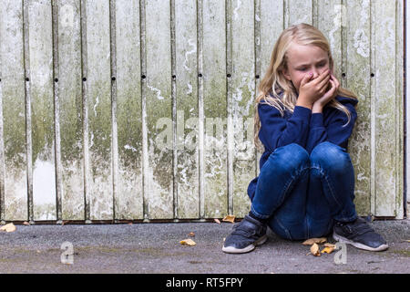 Verängstigten Mädchen Hocken vor der hölzernen Wand Stockfoto