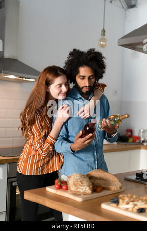 Paar steht in der Küche und bereitete das Abendessen Partei, die Wahl Wein Stockfoto