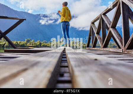 Chile Chaiten, Lago Rosselot, Frau stehend auf Jetty holding Becher Stockfoto