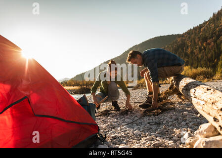 Reifes Paar camping am Flußufer mit Holz für ein Lagerfeuer. Stockfoto