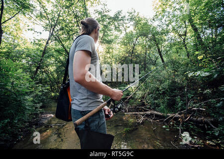 Rückansicht des jungen Mann angeln in einem Wald Stockfoto