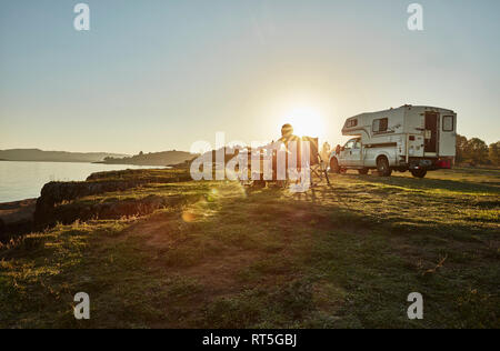 Chile, Talca, Rio Maule, Camper am See mit Frau und Hund bei Sonnenuntergang Stockfoto