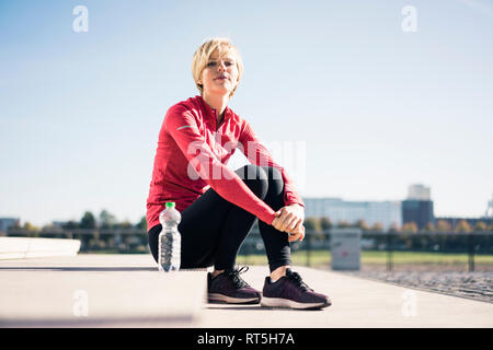 Junge Frau am Ufer sitzen, eine Pause nach dem Training Stockfoto