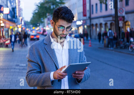 Deutschland, München, junger mit digitalen Tablet in der Stadt in der Dämmerung Geschäftsmann Stockfoto