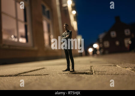 Geschäftsmann Figur steht in der Straße vor Häusern Stockfoto