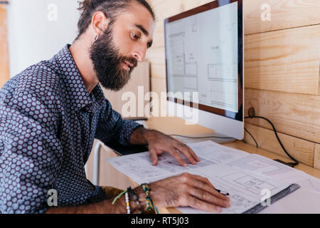 Der junge Architekt zu Hause mit Blueprints und Computer arbeiten Stockfoto