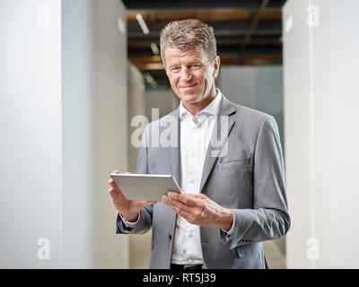 Portrait von lächelnden Geschäftsmann mit Tablette auf Bürobereich Stockfoto