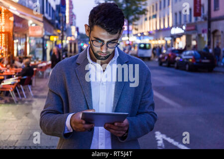 Deutschland, München, junger mit digitalen Tablet in der Stadt in der Dämmerung Geschäftsmann Stockfoto