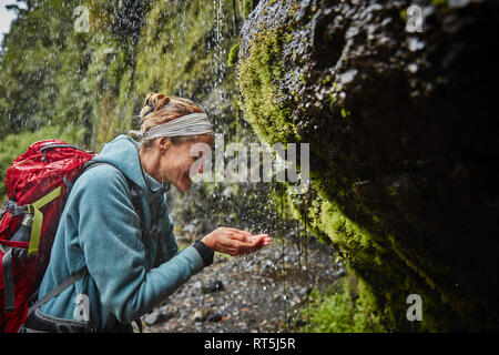 Chile, Patagonien, Vulkan Osorno, Frau erfrischend, mit Wasser von Las Cascadas Wasserfall Stockfoto