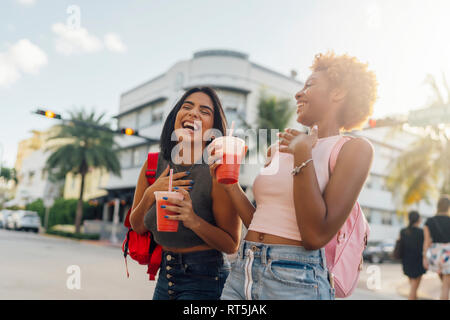 USA, Florida, Miami Beach, zwei Glückliche weibliche Freunde mit einem alkoholfreien Getränk in der Stadt Stockfoto