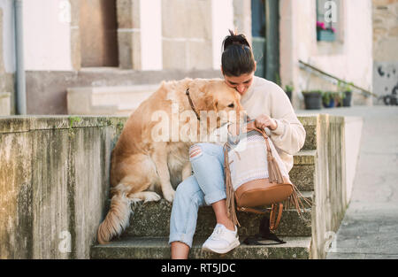 Junge Frau mit ihrem Golden Retriever Hund auf Treppe im Rucksack suchen Stockfoto