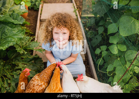 Portrait von kleinen Mädchen Fütterung Hühner in Zuteilung Stockfoto