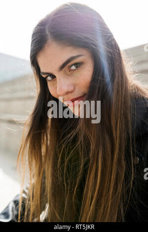 Portrait von selbstbewussten jungen Frau mit langen braunen Haaren im Freien Stockfoto