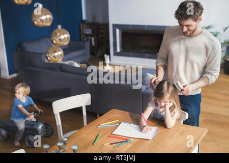 Vater bürsten Haare's Tochter, während Sie zeichnen Stockfoto