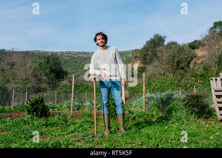 Junge Landwirt im Gemüsegarten mit Strohhut und eine Hacke Stockfoto