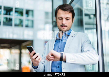 Porträt eines Geschäftsmannes checkin Zeit mit Smartphone Stockfoto