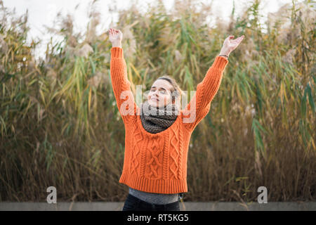 Porträt der lächelnde Frau trägt orange Strickpullover und Schal im Herbst Stockfoto