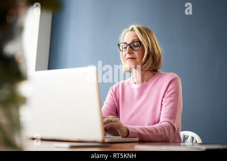 Reife Frau mit Laptop zu Hause Stockfoto