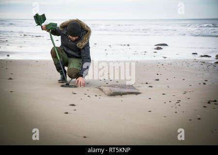 Mann mit Metalldetektor am Sandstrand Stockfoto