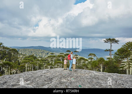 Chile, Puren, El Melado Nationalpark, stehende Frau mit Söhnen auf Boulder bei Araucaria Forest suchen Stockfoto