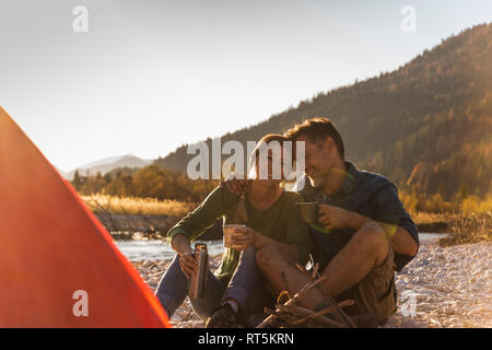 Reifes Paar camping am Flußufer im Abendlicht Stockfoto