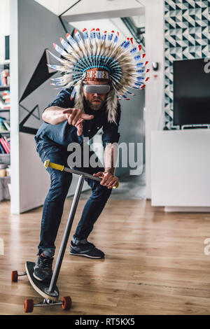 Mann mit indischen Kopfschmuck und VR-Brille in Büros über Kick scooter Stockfoto