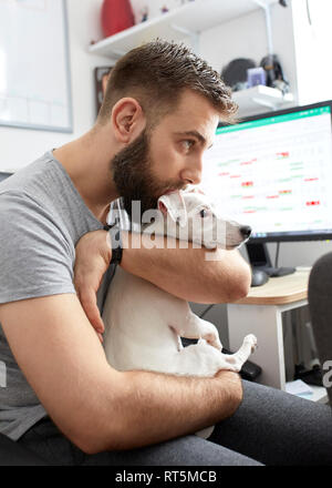 Mann seinen Hund kuscheln zu Hause Büro Stockfoto