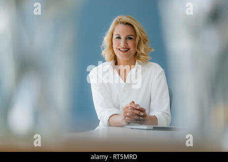 Portrait von lächelnden Geschäftsfrau am Tisch sitzen Stockfoto