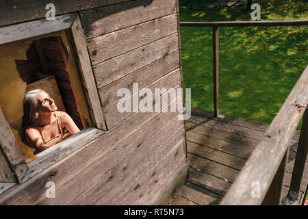 Frau in Tree House genießen Sonnenlicht Stockfoto