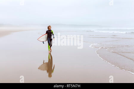 Spanien, Aviles, junge Surfer Surfbrett Durchführung am Strand Stockfoto