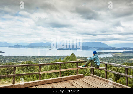 Chile, Puren, El Melado Nationalpark, Frau sitzt auf der Aussichtsterrasse mit Blick auf den See Stockfoto