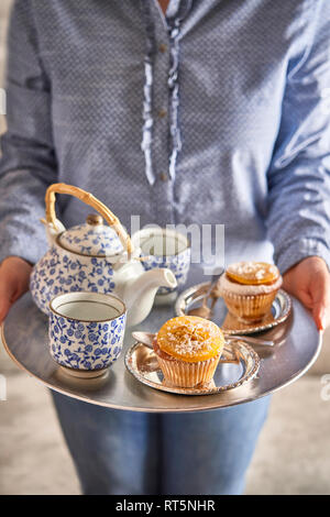 Frau mit frischen Muffins und Tee auf silbertablett Stockfoto