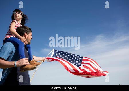 Mann mit Tochter und amerikanische Flagge unter blauem Himmel Stockfoto