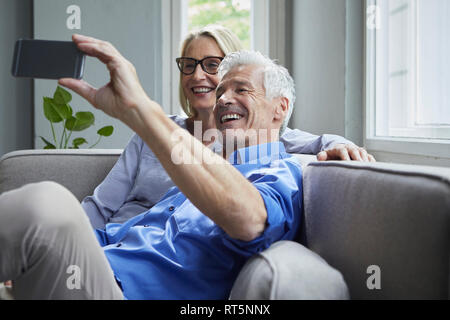 Gerne reifes Paar sitzt auf der Couch zu Hause einen selfie Stockfoto