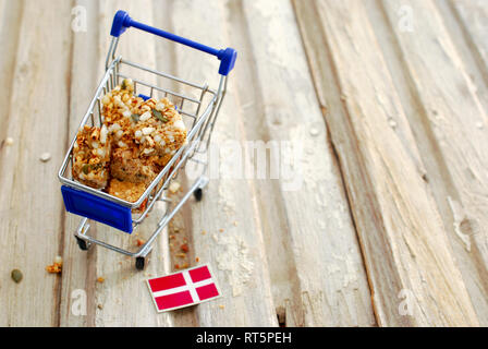 Shopping Cart mit Cornflakes-Stücke und Flag od Dänemark auf Holz Hintergrund, Bild Stockfoto