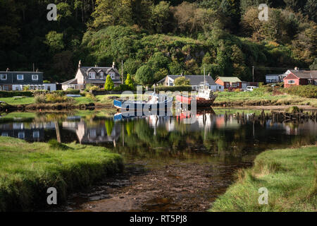 Fischerboote vor Häusern günstig bei Waterfoot in der Nähe des Dorfes Carradale auf der Halbinsel Kintyre an einem sonnigen Nachmittag. Stockfoto