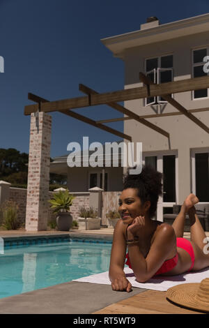 Frau entspannend in der Nähe von Schwimmbad an einem sonnigen Tag Stockfoto